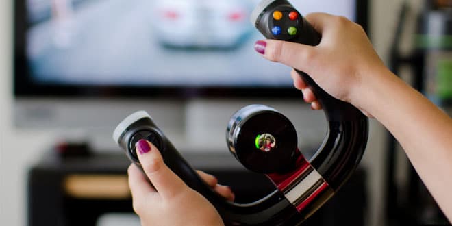 A woman is holding a racing wheel gaming controller in front of a tv.