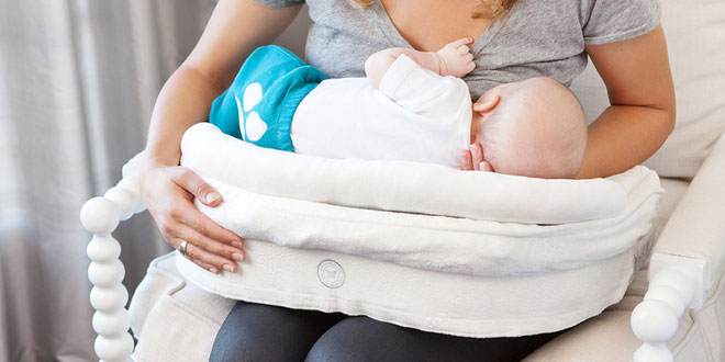 A woman is holding a baby in a nursing chair.