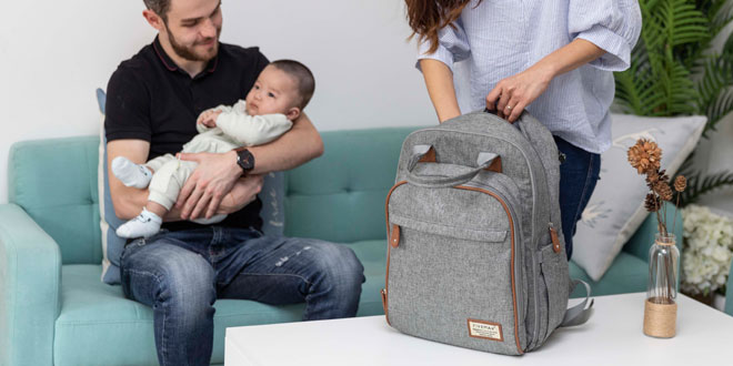 A man and woman holding a baby in a gray backpack.