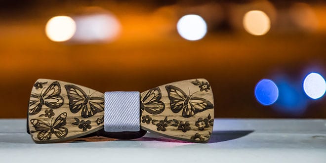 A wooden bow tie with butterflies on it.