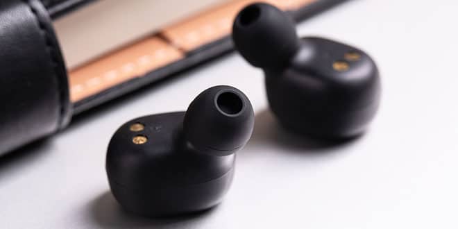 Two black earphones sitting next to each other.