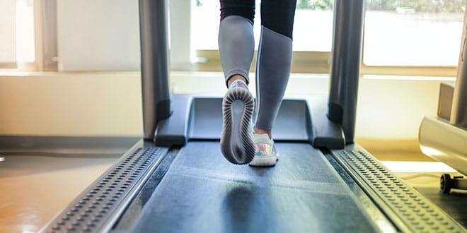 A person is running on a treadmill in a gym.