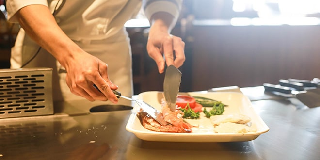 A chef is slicing a piece of meat on a plate.