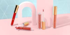Lip glosses and lipsticks on a pink background.