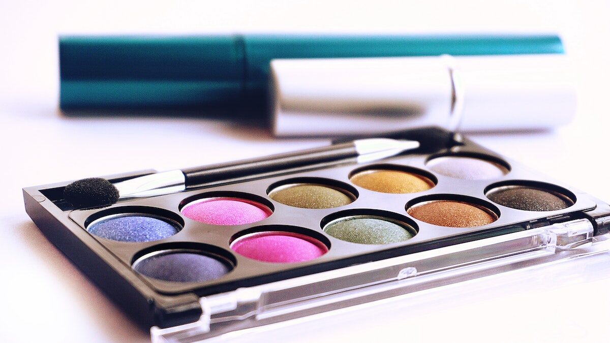 An eyeshadow palette and a lipstick on a white surface.