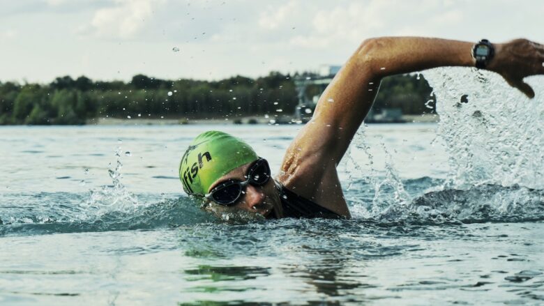 A swimmer is swimming in the water with a goggles on.