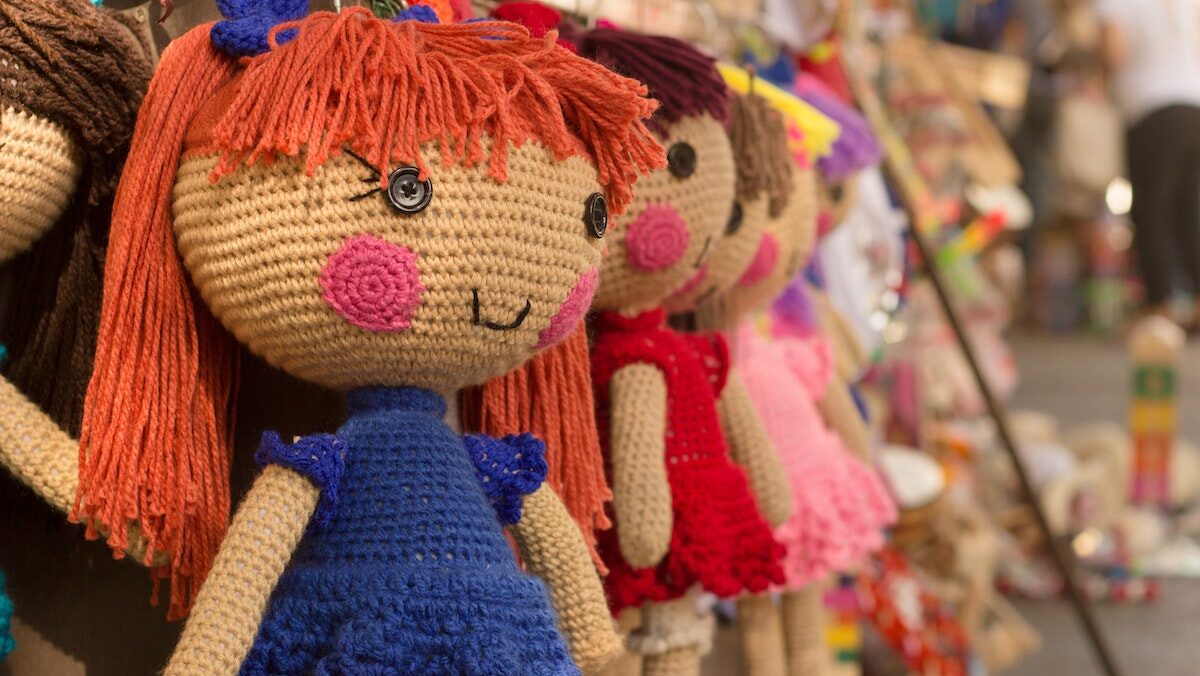 A row of brown purple red knitted crocheted dolls.