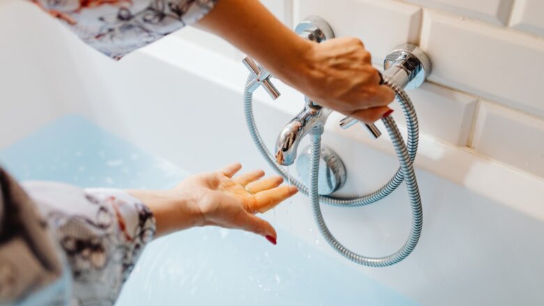 A woman is washing her hands in a bathtub.