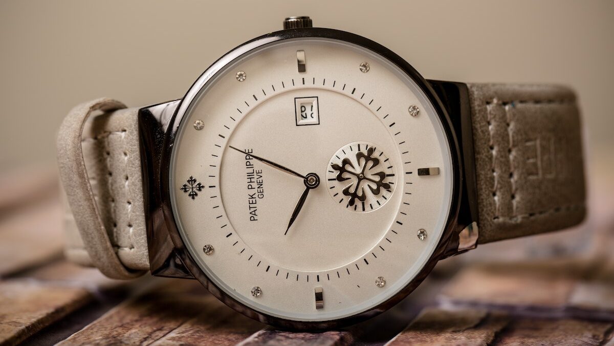 A luxury wrist watch for men with a beige strap sitting on a wooden table.