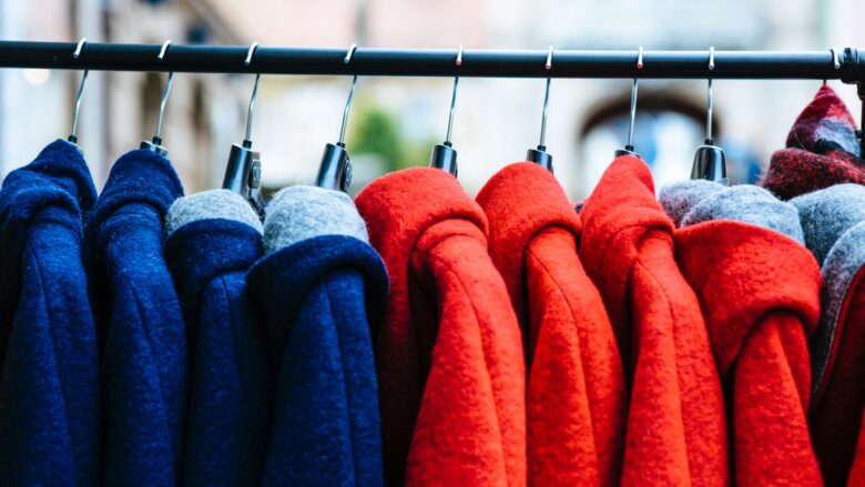 A row of red, blue, and green sweaters hanging on a rack.